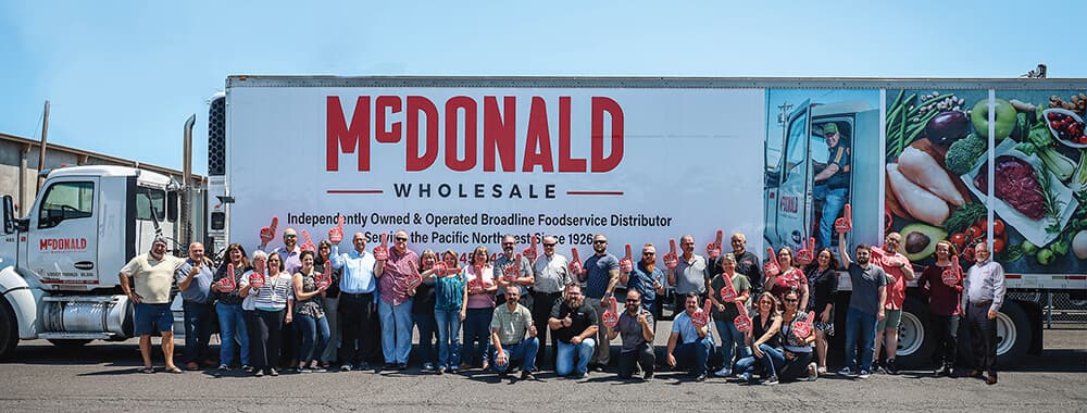 The McDonald Wholesale team in front of a branded delivery truck reading Independently Owned and Operated Broadline Foodservice Distributor, Serving the Pacific Northwest Since 1926